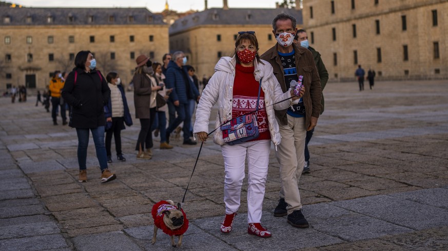 People wearing face masks to curb the spread of COVID-19 walk in San Lorenzo de El Escorial, Spain, Sunday, Jan. 2, 2022. Spanish officials have taken pride in a successful vaccination rollout that ha ...