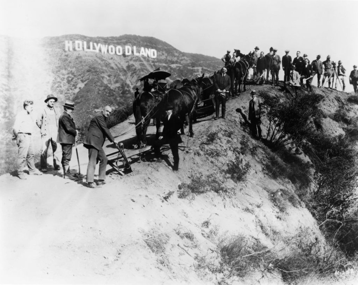 LOS ANGELES - CIRCA 1925: A group of men most likely Surveyors and builders working on the new housing developement known as Hollywoodland pose for a portrait beneath the sign that was erected to adve ...
