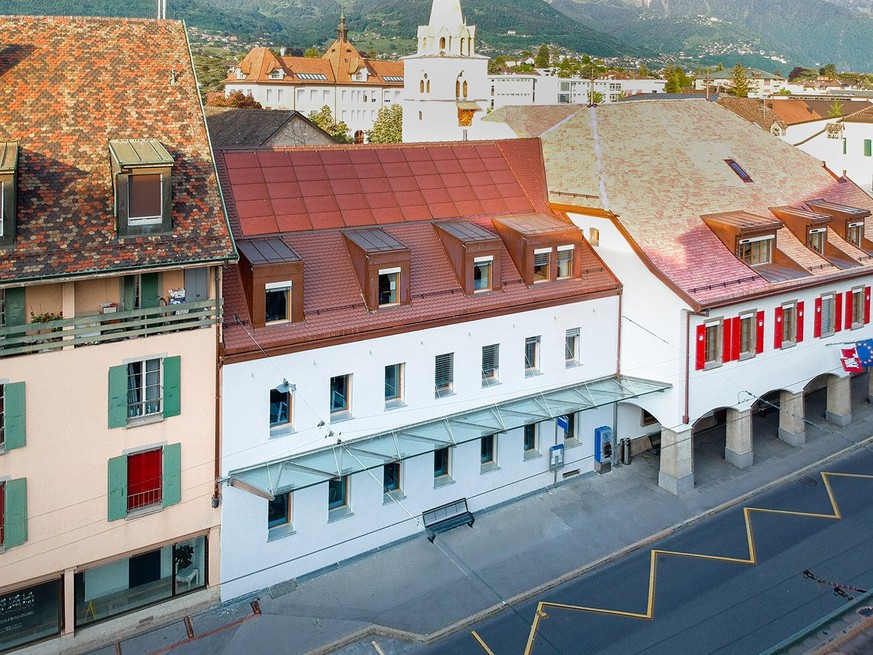 Das Bild zeigt ein historisches Verwaltungsgebäude in La Tour-de-Peilz VD mit einer integrierten, farblich an die Ziegel angepassten Photovoltaikanlage.
