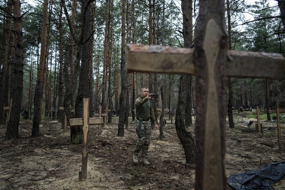 Oleg Kotenko, the Commissioner for Issues of Missing Persons under Special Circumstances uses his smartphone to film the unidentified graves of civilians and Ukrainian soldiers in the recently retaken ...