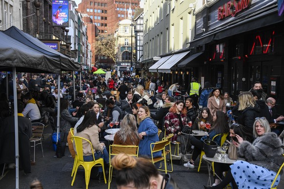 People sit, drinking and eating, outside cafes and pubs Soho, central London, on the day some of England's coronavirus lockdown restrictions were eased by the British government, Monday, April 12, 202 ...