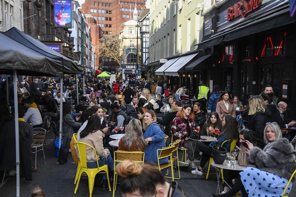 People sit, drinking and eating, outside cafes and pubs Soho, central London, on the day some of England&#039;s coronavirus lockdown restrictions were eased by the British government, Monday, April 12 ...