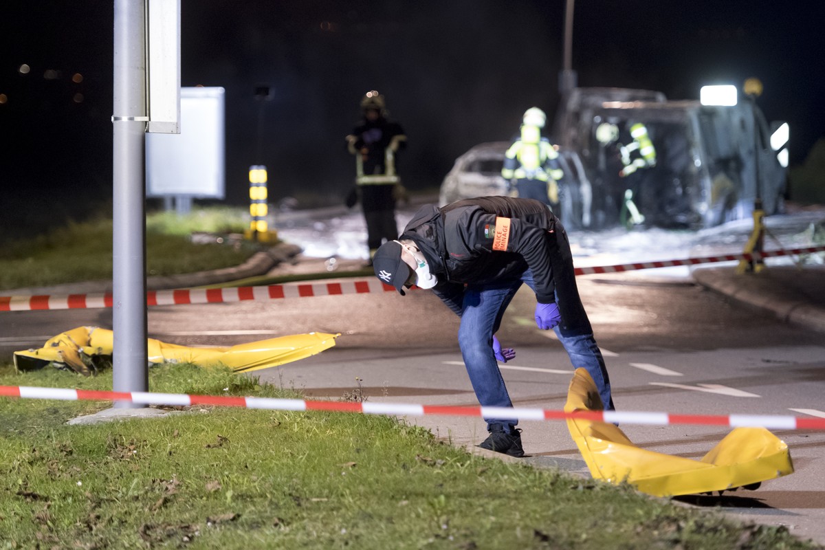 Un policier scientifique observe des pieces du fourgon blinde a proximite de trois vehicules calcines a la sortie du village apres l'attaque d'un fourgon de transport de fonds ce lundi 2 dec ...