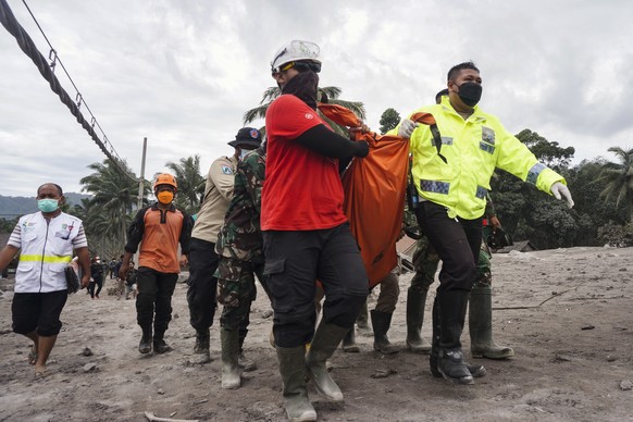 epa09625051 Rescuers carry the body of a victim at an area affected by the eruption of Mount Semeru in Lumajang, East Java, Indonesia, 06 December 2021. The volcano erupted on 04 December, killing at  ...