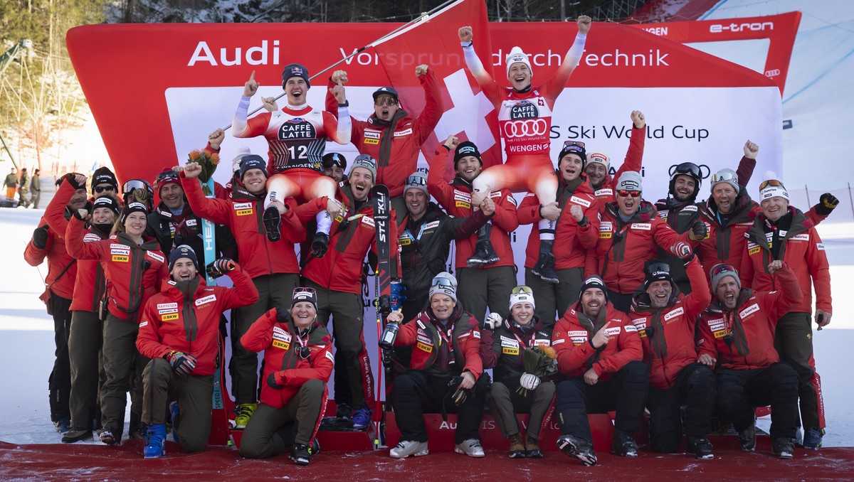 epa11834016 Second placed Franjo von Allmen of Switzerland, top left, and winner Marco Odermatt of Switzerland, top right, celebrate with their team members on the podium for the Men's Downhill r ...