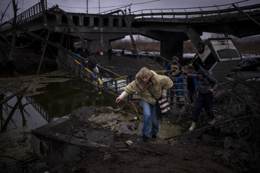 A woman runs as she flees with her family across a destroyed bridge in the outskirts of Kyiv, Ukraine, Wednesday, March 2. 2022. Russia renewed its assault Wednesday on Ukraine���s second-largest city ...
