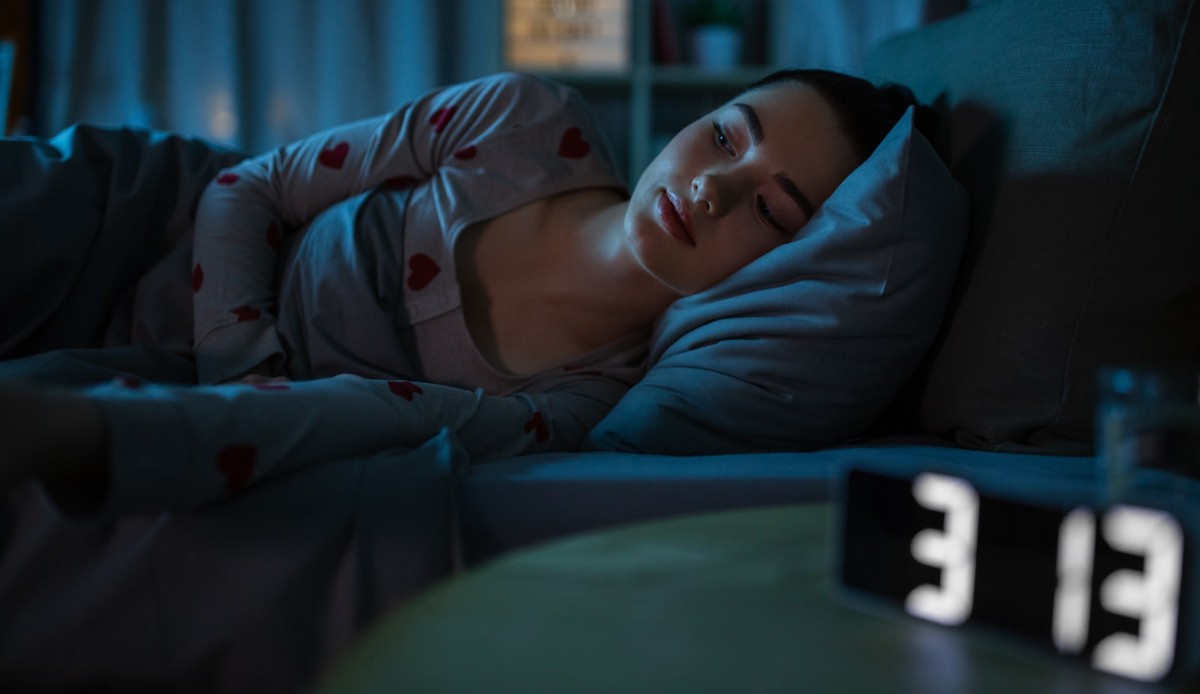 people, bedtime and insomnia concept - awake teenage girl lying at home at night