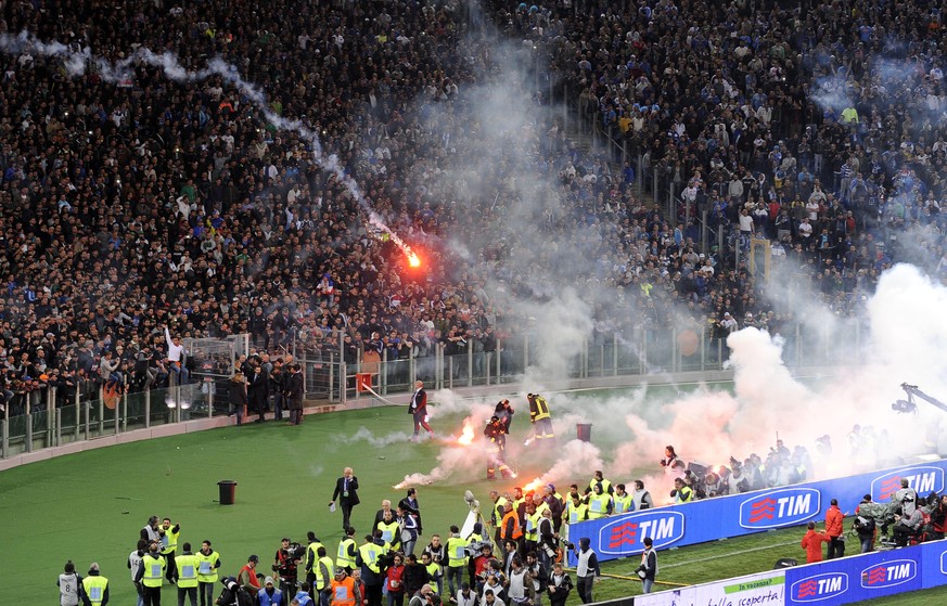 Aus der Napoli-Kurve fliegen Leuchtpetarden in Richtung Spielfeld.