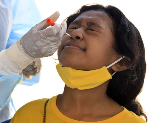 epa09428468 A girl reacts as a healthcare worker collects her specimen samples during a COVID-19 swab test in Dili, East Timor, also known as Timor Leste, 25 August 2021. East Timor has recorded more  ...