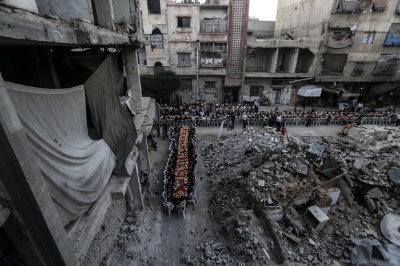 epa06034552 People wait for Iftar, evening meal at the end of daily Ramadan fast at sunset, next to rubble and destroyed houses, which were damaged after air strikes, in Douma, Syria, 17 June 2017. Mu ...