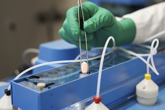 FILE - In this photo provided by Pfizer, a technician handles one of the company&#039;s COVID-19 Paxlovid pills. COVID-19 patients have two new treatment options that can be taken at home. But that co ...