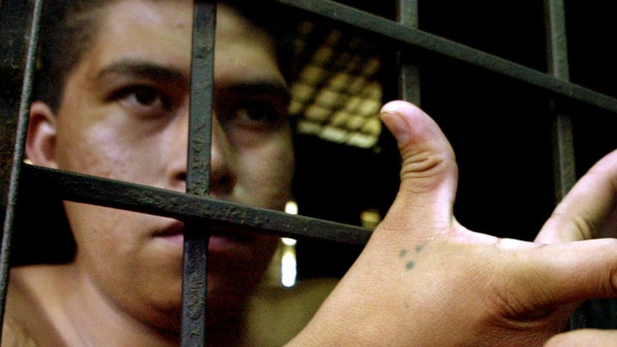 &quot;The Brother,&quot; 25, a gang member of &quot;Mara 18,&quot; stands behind a prison cell in San Bartolo, east of San Salvador, El Salvador, Friday, Feb. 18, 2005. (AP Photo/Luis Romero) ** EFE O ...