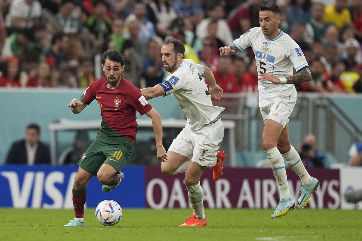Portugal's Bernardo Silva, left, challenges for the ball with Uruguay's Diego Godin, centre, during the World Cup group H soccer match between Portugal and Uruguay, at the Lusail Stadium in  ...