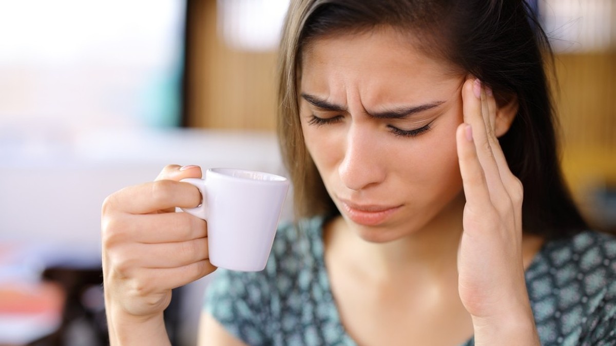 Frau mit Kaffee, Kopfschmerzen (Symbolbild)