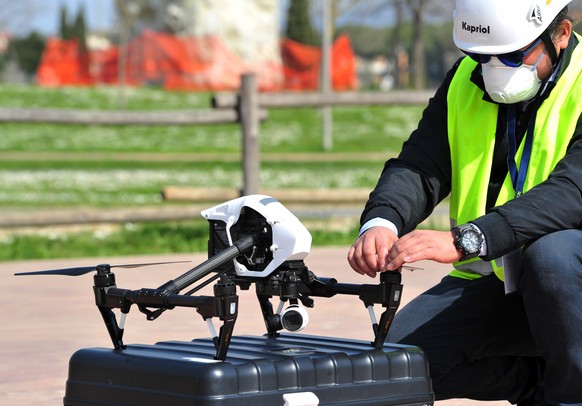 In this Friday, March 20, 2020, photo, a police officer with help from a drone monitor citizens&#039; movements demonstrates in Grosseto, central Italy. European governments are evaluating invasive hu ...