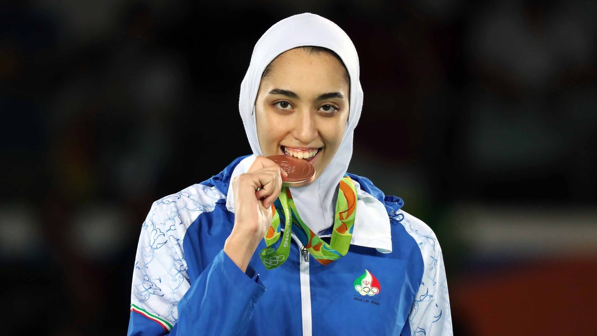 epa08122435 (FILE) - Joint bronze medalist Kimia Alizadeh Zenoorin of Iran bites her medal as she poses on the podium for the women's -57kg competition of the Rio 2016 Olympic Games Taekwondo eve ...