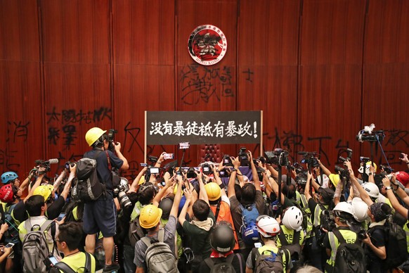 epaselect epa07687469 Members of the press take pictures of a protest banner that says &#039;there are no violent people, only violent governance&#039; after protesters break into the main chamber of  ...