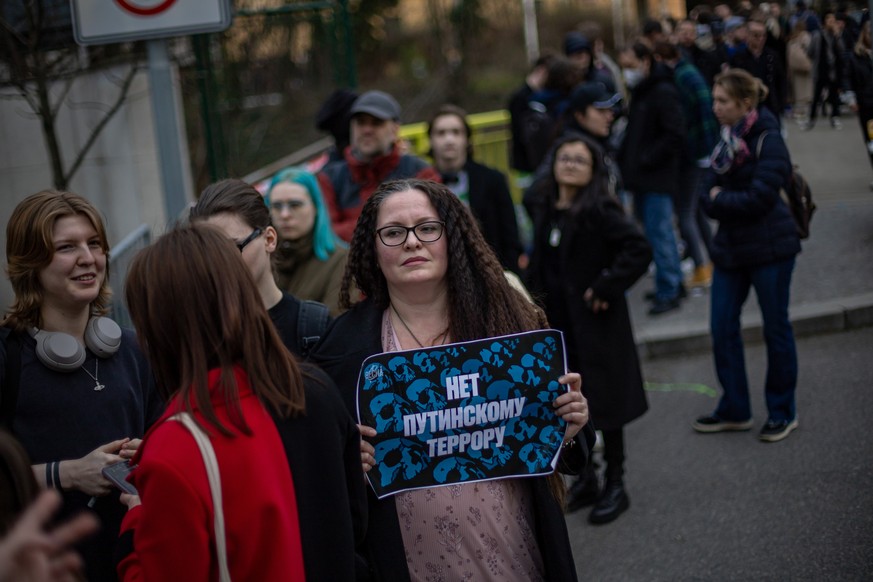 epa11222868 A woman holds placard reading &#039;No to Putin&#039;s terror&#039; as Russian citizens wait in line to vote in presidential elections at the Russian embassy in Prague, Czech Republic, 15  ...