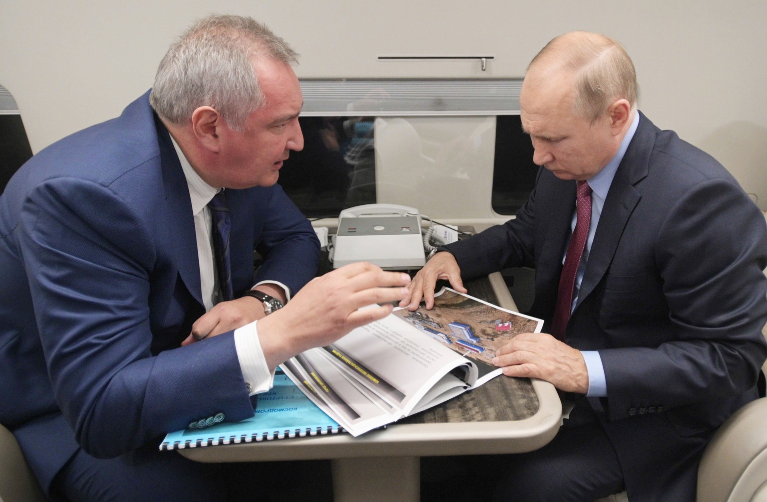 FILE - Russian President Vladimir Putin, right, and Russian Roscosmos head Dmitry Rogozin talk to each other aboard of the Presidential plane on their way to visit the Vostochny cosmodrome outside the ...