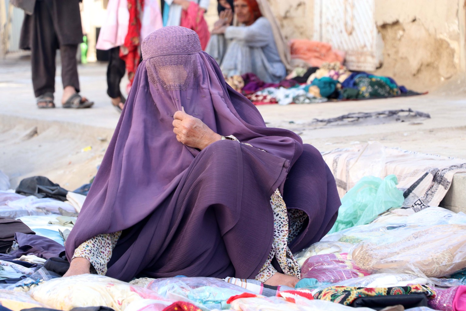 epa10507093 Afghan women sell used clothes on a road side on the eve of World Women Day, in Kandahar, Afghanistan, 07 March 2023. World Women Day is observed across the world on 08 March with this yea ...