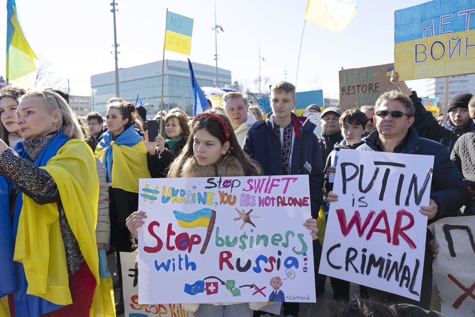 epa09786213 Demonstrators hold placards while protesting against Russia&#039;s massive military operation against Ukraine during a rally on the place of the United Nations in Geneva, Switzerland, 26 F ...