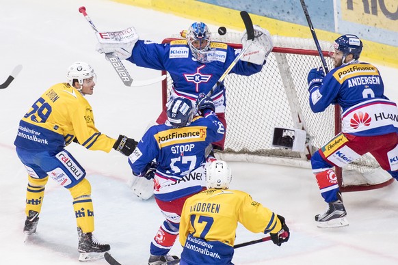 Davoser Dario Simion, links, spielt um den Puck gegen Goalie Luca Boltshauser, Mitte von Kloten waehrend dem Eishockey-Meisterschaftsspiel der National League zwischen den EHC Kloten und dem HC Davos  ...