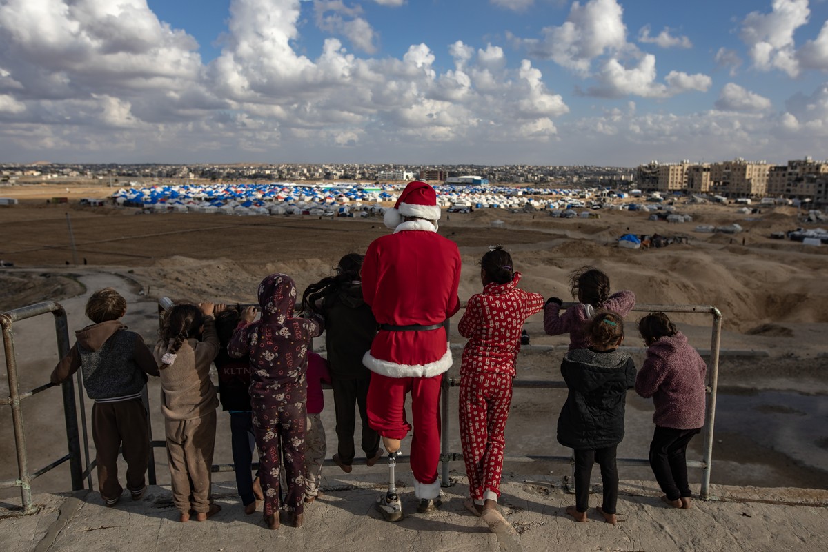 epaselect epa11807837 Amr Abu Hashem (C), a 26-year-old displaced Palestinian from Khan Younis, dressed as Santa Claus to tour the destroyed homes and temporary tent shelters of displaced families in  ...