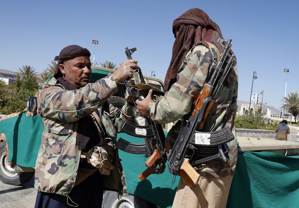 epa09719770 A Houthi fighter (L) takes his gun from his comrade during a mass funeral of 20 slain Houthi fighters who were killed in escalating fighting against Saudi-UAE backed government forces, in  ...