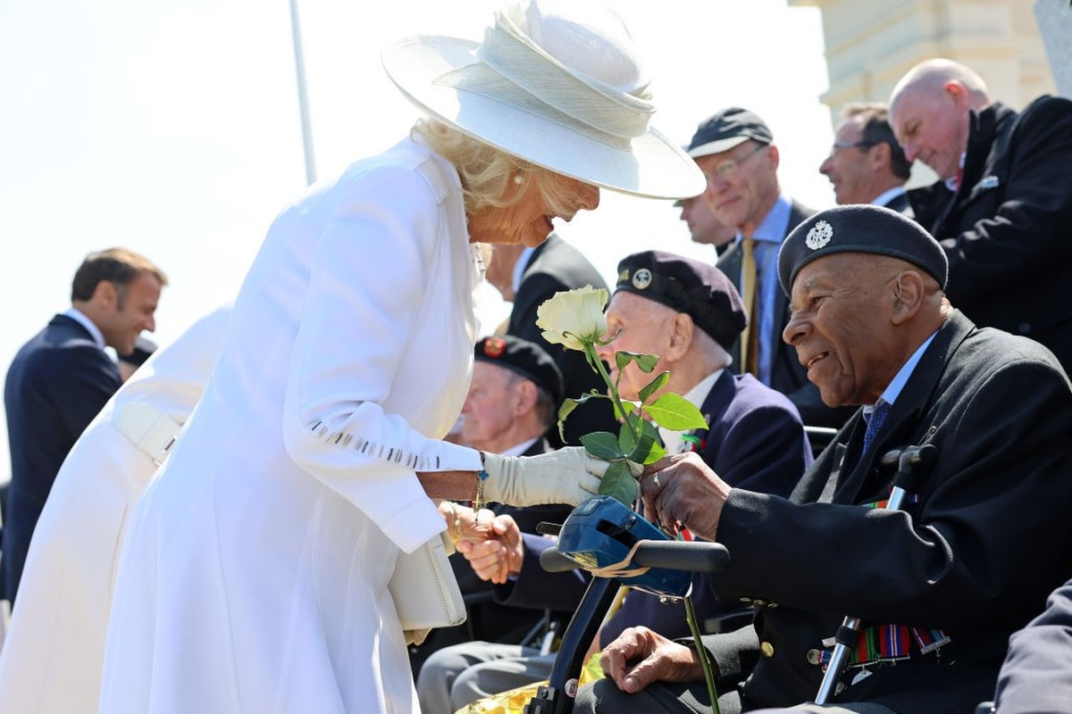 VER-SUR-MER, FRANCE - JUNE 06: Queen Camilla receives a white rose from a veteran during the UK Ministry of Defence and the Royal British Legion’s commemorative event at the British Normandy Memorial  ...