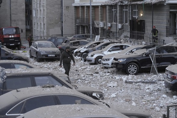 A police officer walks at the parking with damaged cars in front of a multi-story apartment building which was damaged during Russian attack in Kyiv, Ukraine, Tuesday, May 30, 2023. (AP Photo/Roman Hr ...
