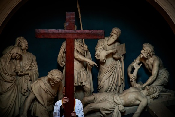 epaselect epa08355611 A priest carries a cross during the procession of the Station of the Cross preceding Easter Celebrations at the Catholic Church of Saint Roch (Saint of Doctors and Intercessor of ...