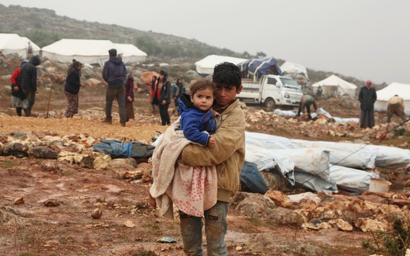 epa08100426 Displaced Syrian children look on as adults set up tents, after fleeing violence of Maarat al-Numan town, near the Turkish border, Northern Syria, 28 December 2019 (issued 03 January 2020) ...