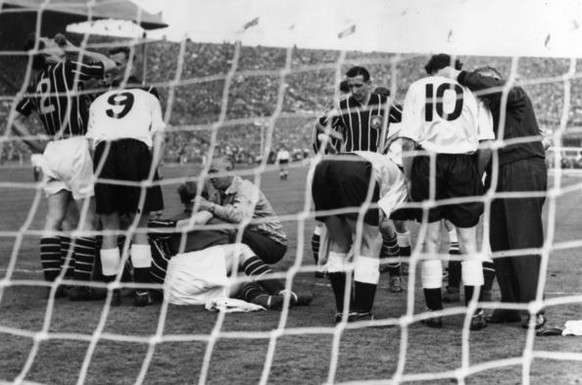 Players gather round the goal mouth as Manchester City&#039;s goalie, Bert Trautmann, receives medical attention to his neck, during the FA cup final against Birmingham City at Wembley. Manchester Cit ...