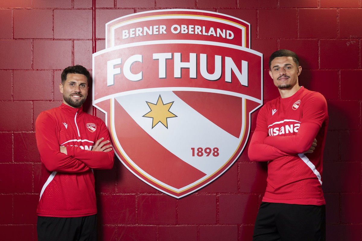 Leonardo Bertone, links, und Elmin Rastoder, Spieler des FC Thun, posieren am Rande eines Interviews vor dem Logo des FC Thun, am Donnerstag, 23. April 2026, in der Stockhorn Arena in Thun. (KEYSTONE/ ...