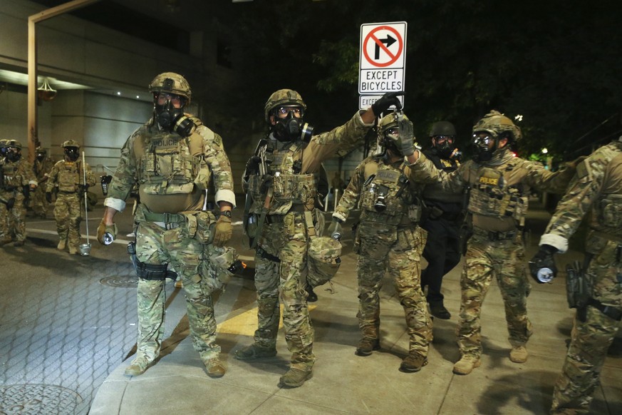 Police respond to protesters during a demonstration, Friday, July 17, 2020 in Portland, Ore. Militarized federal agents deployed by the president to Portland, Oregon, fired tear gas against protesters ...