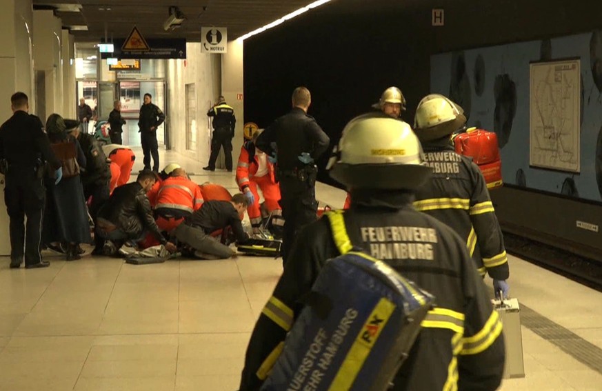 Firefighters treat an injured person at a subway station in Hamburg, Germany, Thursday, April 12, 2018. Police say a woman and her child have died after being stabbed by her ex-husband at a subway sta ...