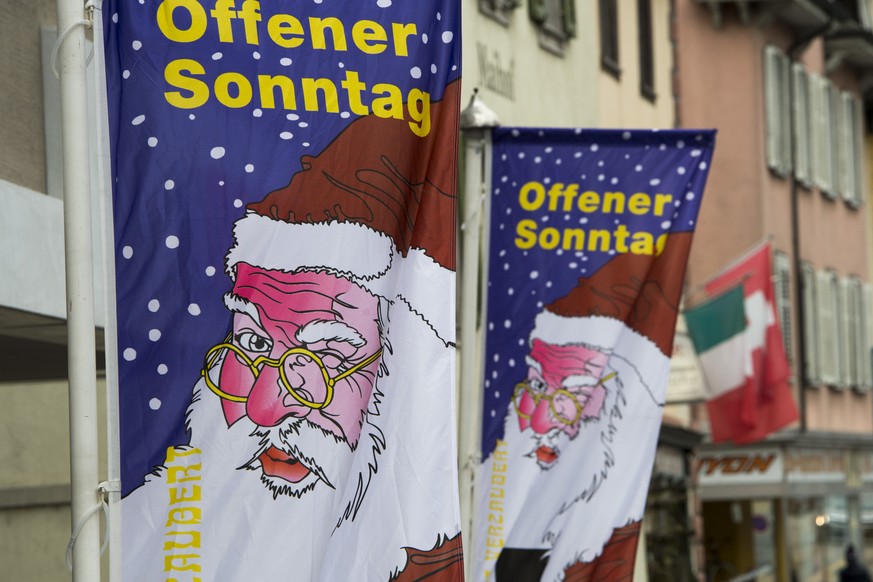 Zwei Fahnen mit dem Slogan &quot;Offener Sonntag&quot; und dem Bild des Samichlaus weisen am Freitag, 28. November 2014, in Kuessnacht auf den verkaufsoffenen Sonntag hin. (KEYSTONE/Sigi Tischler)