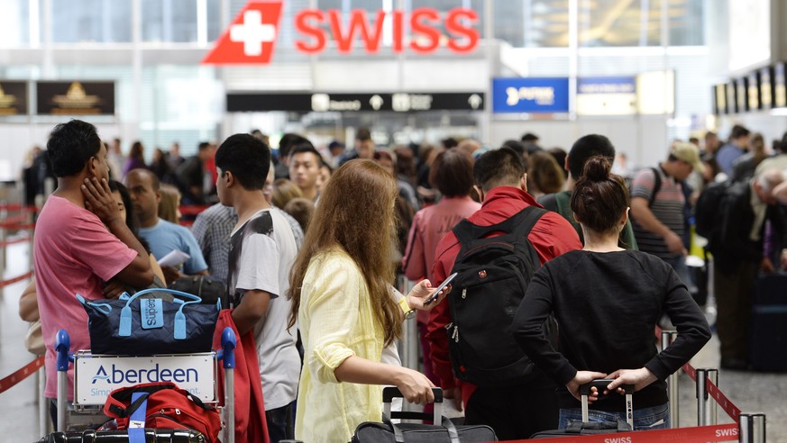 Reisende stehen vor einem Schalter Schlange, am Samstag, 12. Juli 2014, auf dem Flughafen Zuerich Kloten. Mit Beginn der Sommerferien im Kanton Zuerich herrscht auf dem Flughafen Zuerich Kloten Hochbe ...