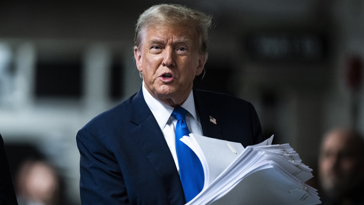 Former President Donald Trump holds print outs of news stories as he speaks to reporters at the end of the day at Manhattan criminal court as jury selection continues for his trial in New York, on Thu ...