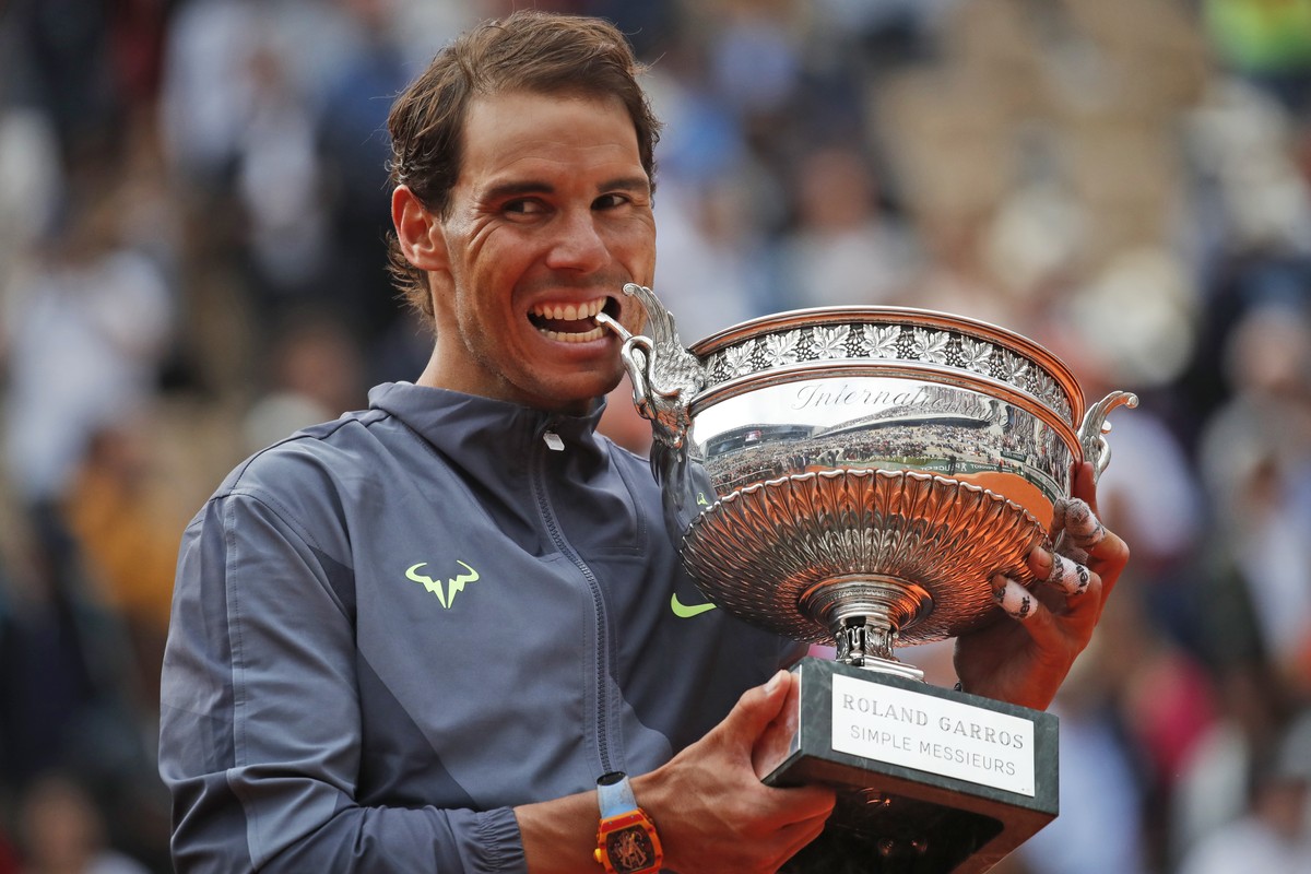 Spain's Rafael Nadal bites the trophy as he celebrates his record 12th French Open tennis tournament title after winning his men's final match against Austria's Dominic Thiem in four se ...