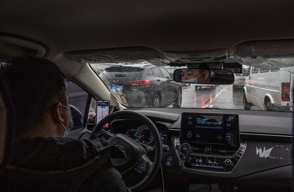 epa08908859 A Didi driver wearing a protective face mask drives a car in Wuhan, China, 29 December 2020. Life in Wuhan, a Chinese city of more than 11 million, which nearly a year ago became the epice ...