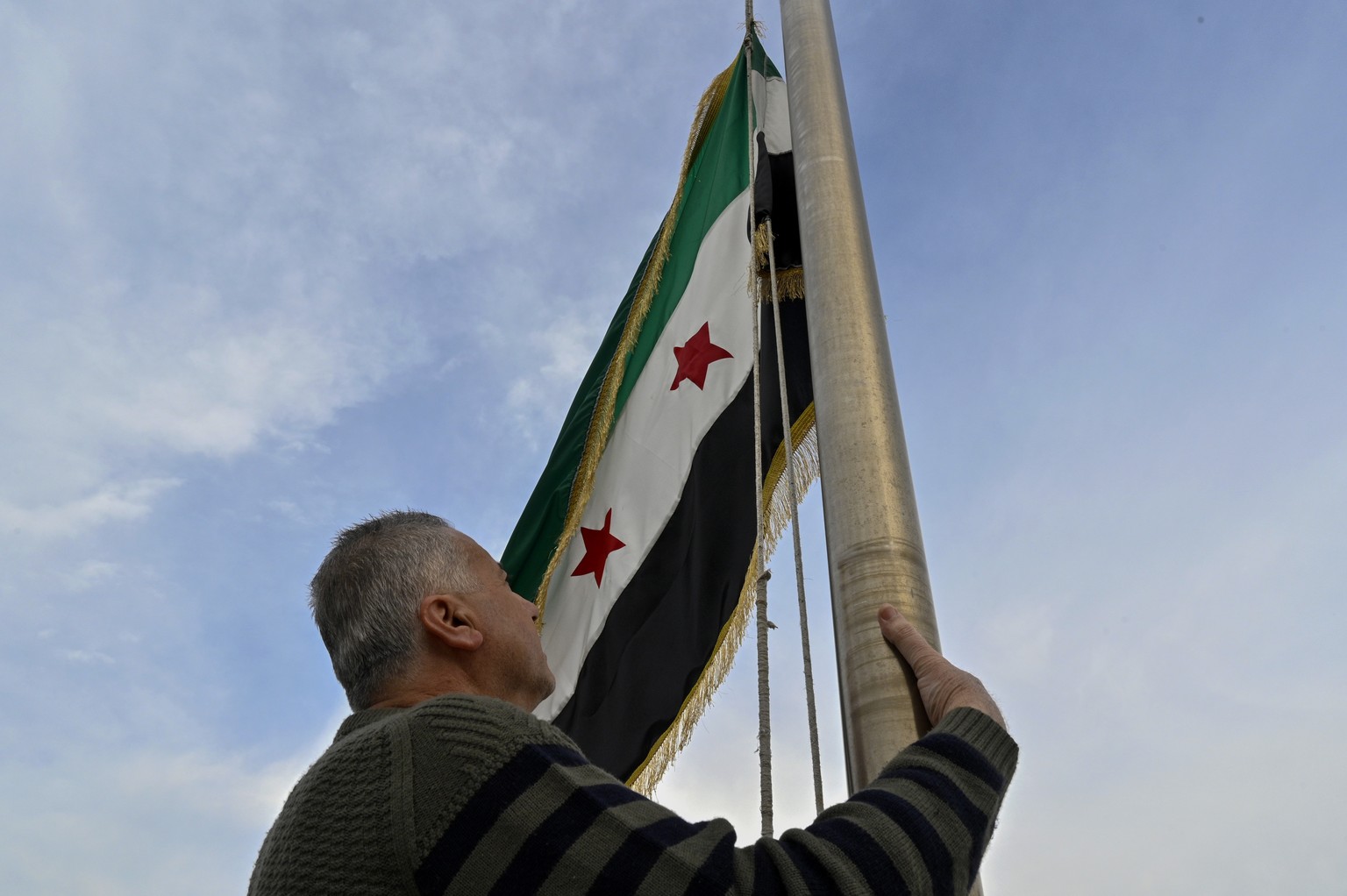 epaselect epa11769886 A man raises the Syrian opposition flag on the Syrian embassy building in Baabda, Lebanon, 11 December 2024. Syrian rebels entered Damascus on 08 December 2024 and announced the  ...