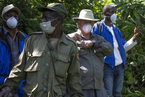 In this photo taken July 30, 2014, a tourist and park rangers wear protective masks as they visit the Virunga National Park in eastern Congo. Congo&#039;s Virunga National Park, home to about a third  ...