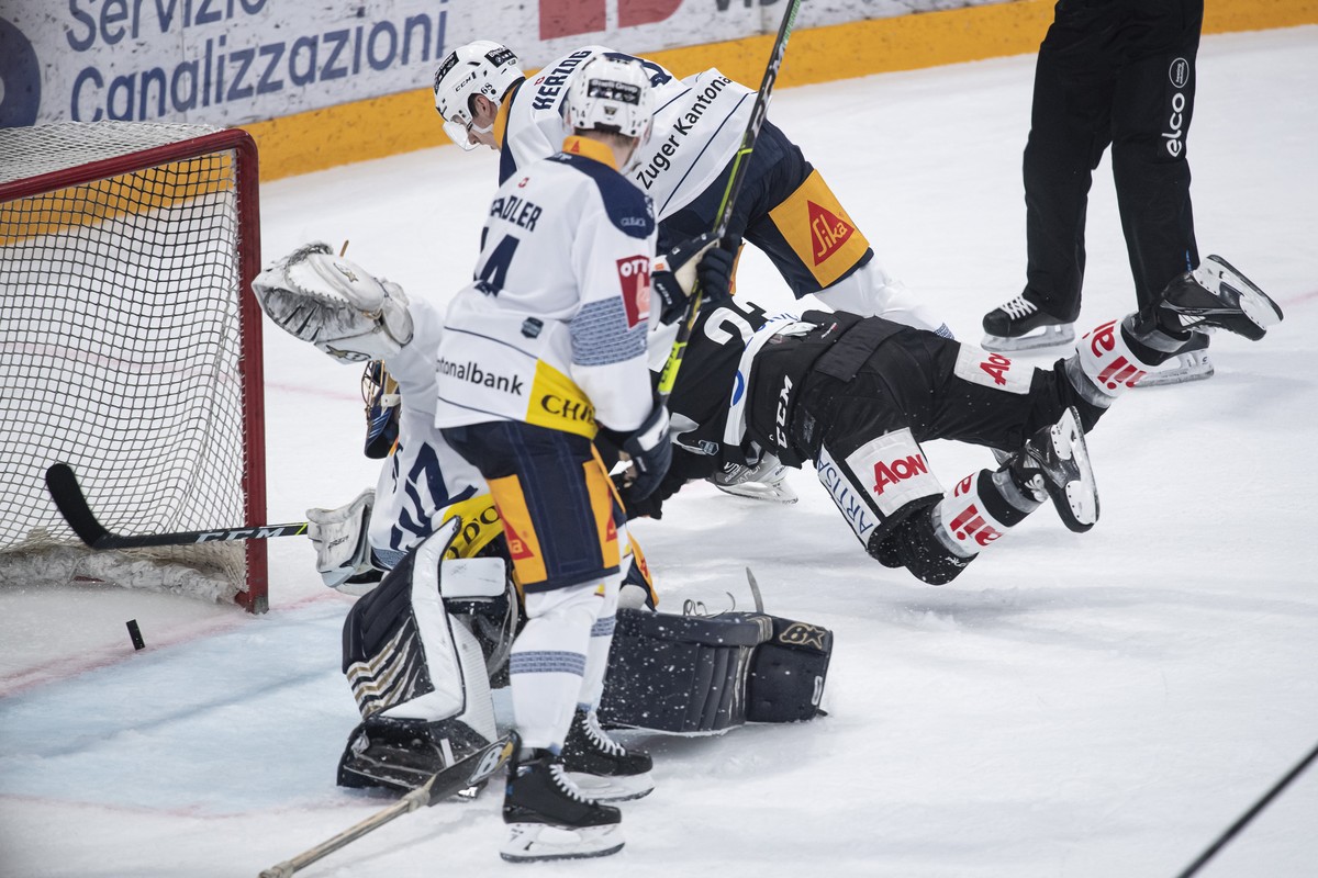 Lugano's player Giovanni Morini, center, shoots the 1-1 goal during the second game of the quarter final playoffs of the National League 2021/22 between HC Lugano against EV Zug at the Corner Are ...