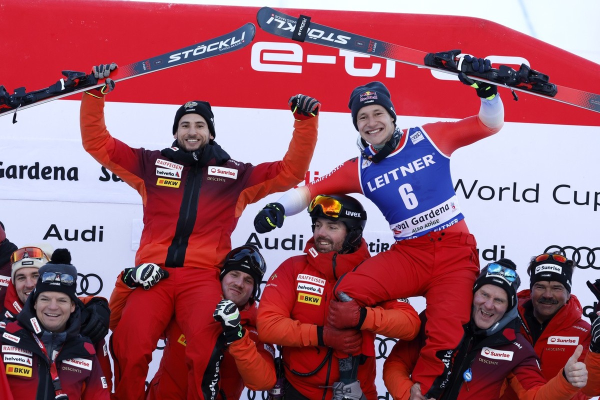 Switzerland's Marco Odermatt, right, third place in an alpine ski, men's World Cup downhill race, celebrates with teammate Marco Kohler, left, and the team, in Val Gardena, Italy, Thursday,  ...