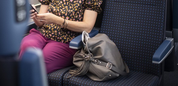 Eine Frau mit Atemschutzmasken faehrt mit dem Zug vom Hauptbahnhof in Zuerich, aufgenommen am Montag, 6. Juli 2020. (KEYSTONE/Ennio Leanza)