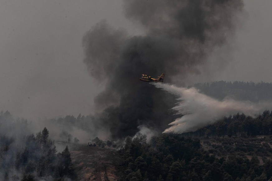210806 -- EVIA, Aug. 6, 2021 -- An aircraft tries to extinguish a wildfire in the north of Evia island, Greece, on Aug. 5, 2021. Greek Prime Minister Kyriakos Mitsotakis said on Thursday evening that  ...