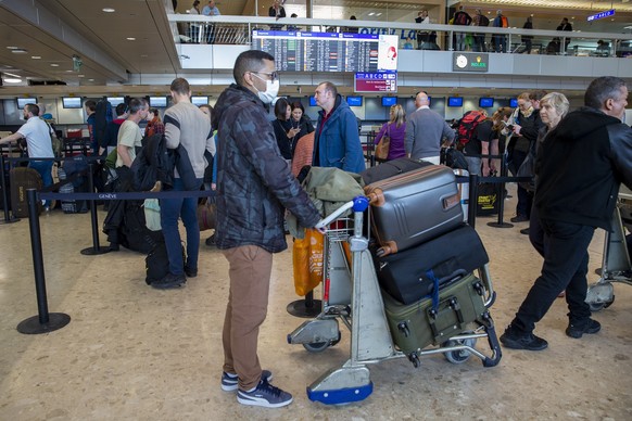 epa08298429 Passengers with their luggages wait in line at the check-in area of the terminal 1 at the Geneve airport after the closing of ski resorts to prevent the spread of the coronavirus COVID-19, ...