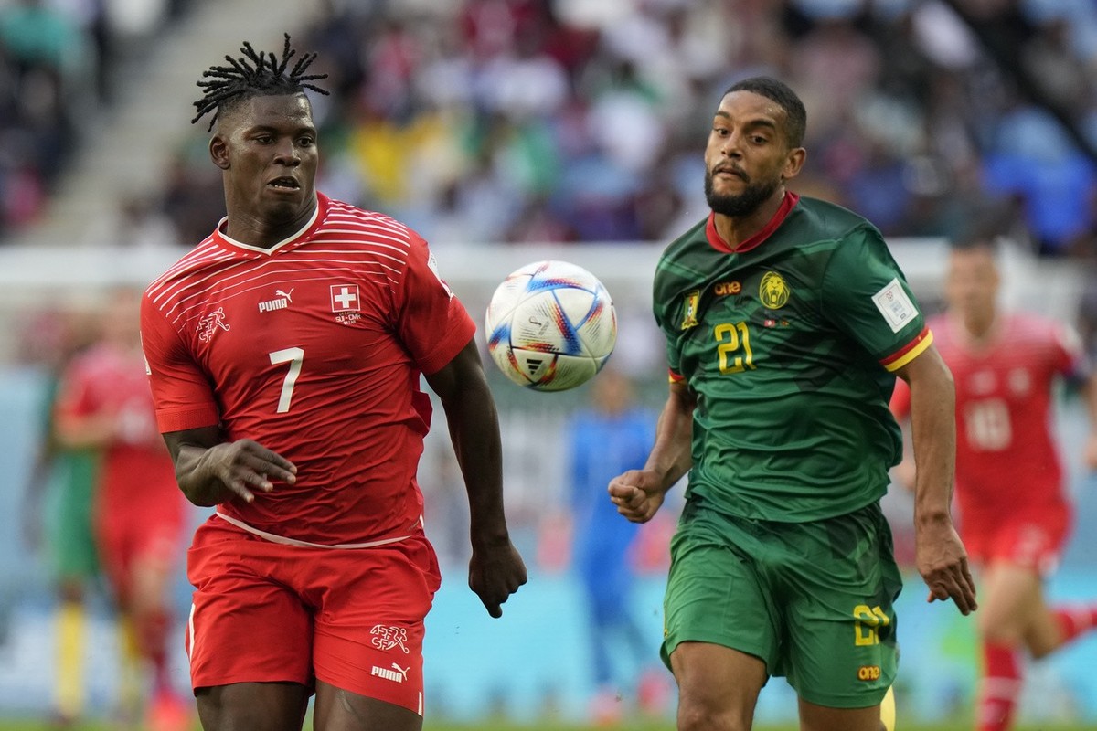 Switzerland's Breel Embolo, left, runs after the ball against Cameroon's Jean-Charles Castelletto during the World Cup group G soccer match between Switzerland and Cameroon, at the Al Janoub ...