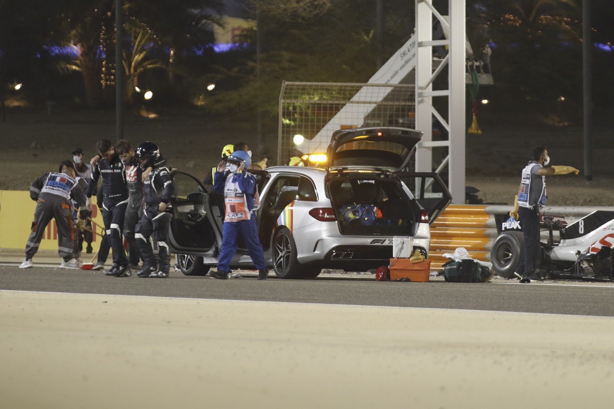 epa08850801 French Formula One driver Romain Grosjean (C-L) of the Haas F1 Team is escorted from the crash site during the start of the Formula One Grand of Bahrain on the Bahrain International Circui ...